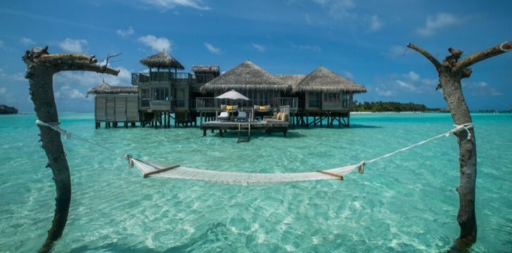 A hammock ties between two large sticks in the ocean