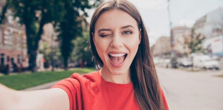 A smiling woman in a red t-shirt blinking.