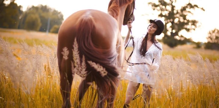 A woman standing by her horse