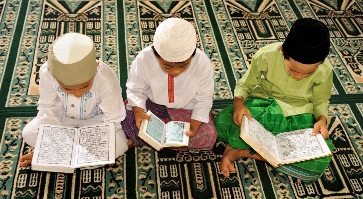 Three children studying the Qu'ran