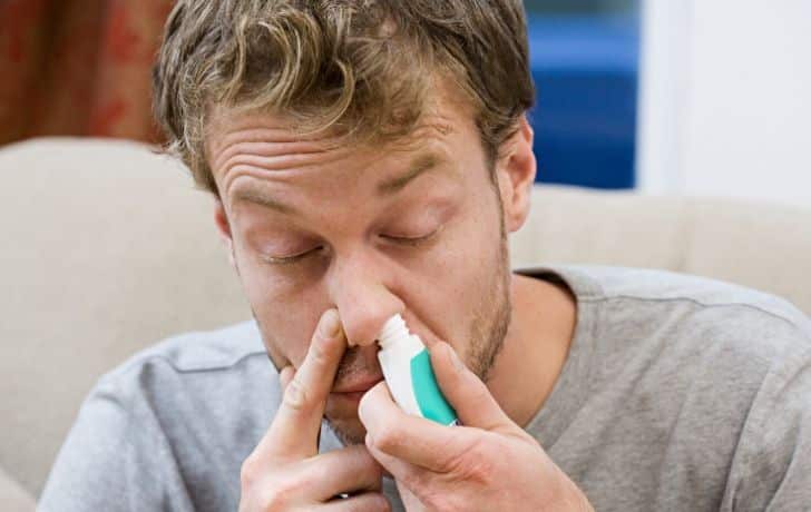 A man using a decongestant spray
