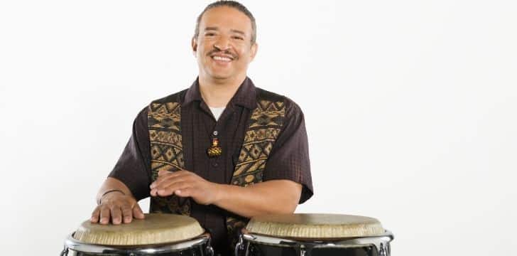 A man smiling behind a pair of Bongo drums.