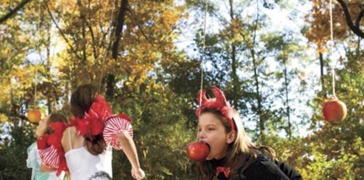 Children grabbing apples on string with their mouth