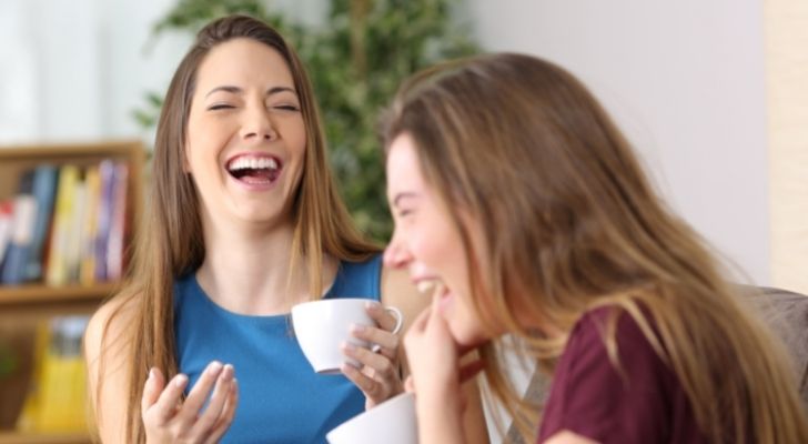 Two women laughing over coffee