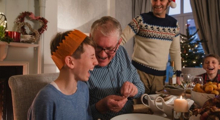 A family sharing a silly Christmas cracker joke at the dining table