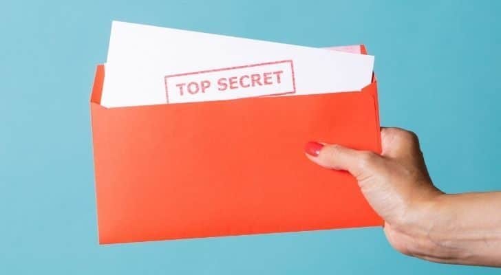 Person holding a piece of paper with the words "top secret" written on it.