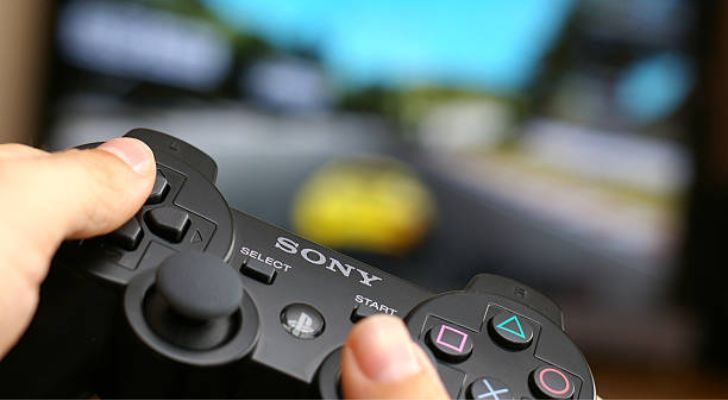 A person playing a game holding a PS3 controller.