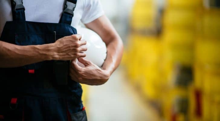 A factory worker holding their protective gear.