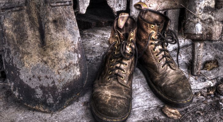 An old pair of Doc Martens next to a shovel.