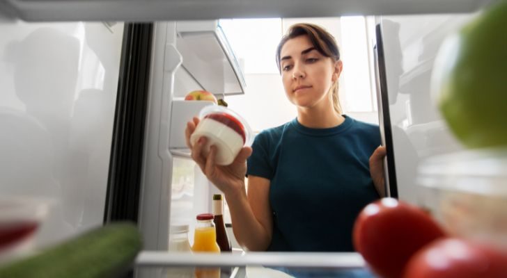 Somebody checking the date on a yogurt in her fridge