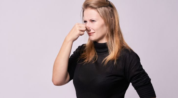 A women holding her nose as she smells something bad