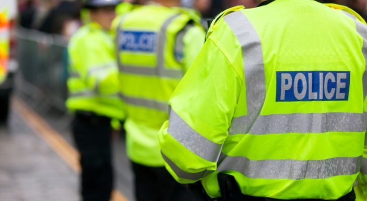 UK police officers line up opposite a crowd on a street