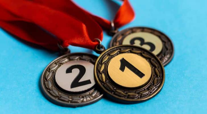 Gold, silver and bronze medals lie on a pale blue surface