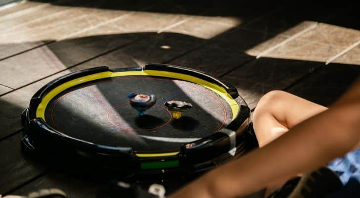 Two Beyblades spin in an arena