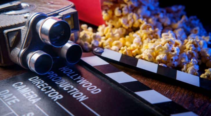 An old fashioned movie camera next to some popcorn and a clapboard