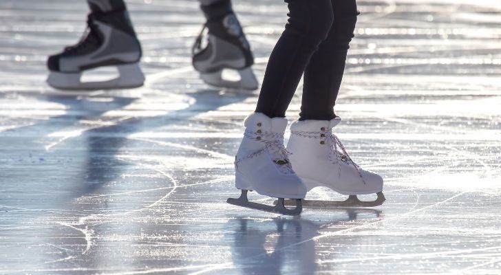 Several people skating on some ice, leaving marks and carvings