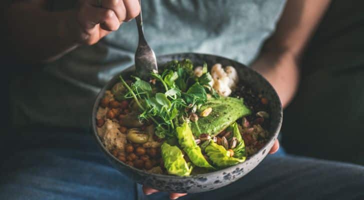 A man eats from a bowl of healthy looking food