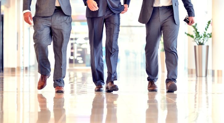 Three businessmen in suits walk while talking