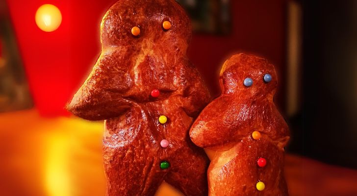 Two human shaped brioche snacks with eyes and buttons made from small candies