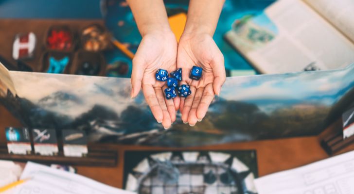 Someone holds several dice over a roleplaying game