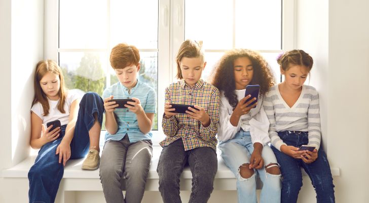 A group of young children looking at their smartphones