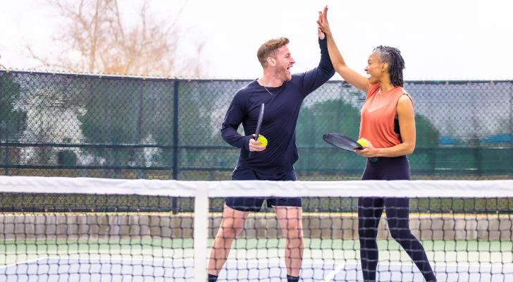 Two friends high five while playing a game of pickleball