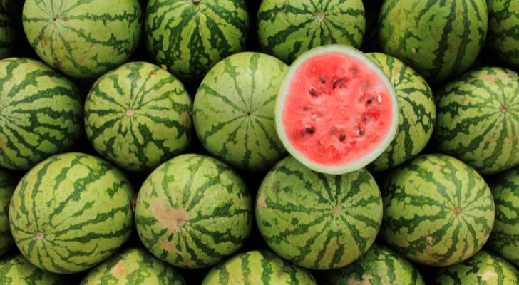 A pile of watermelons with one cut in half