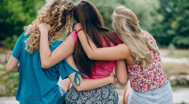 Three female friends sitting next to each other while hugging