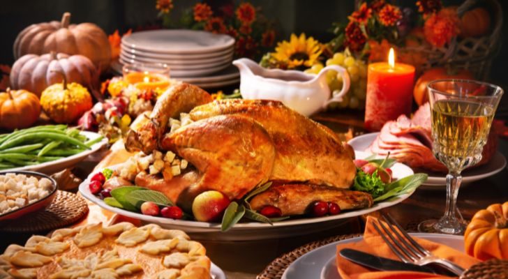 A traditional thanksgiving spread of sides and deserts is set around the a roasted turkey