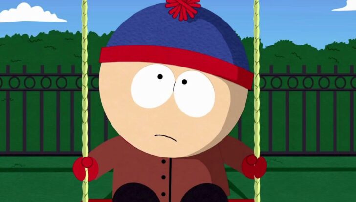 Stan Marsh from South Park sitting on a swing in a park.