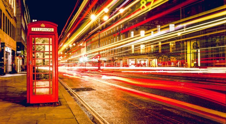 Light blur by on a London street at night next to a classic red phone booth