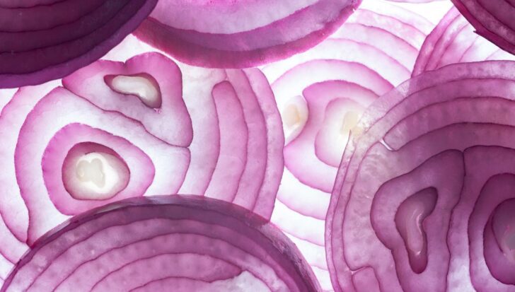 Close-up view of thinly sliced red onions showing their concentric rings and translucent texture