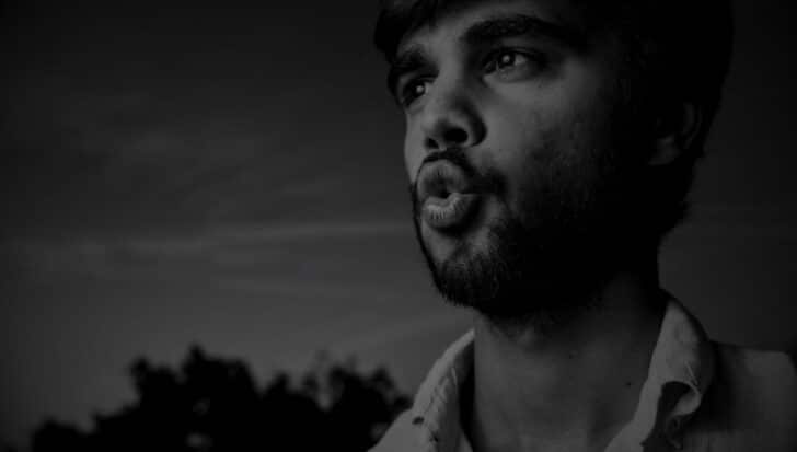 Black and white photo of a person with a beard whistling