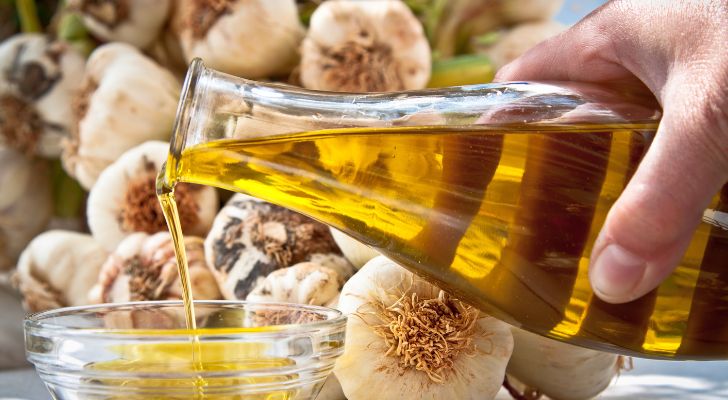 Someone pouring a jar of olive oil into a glass ramekin