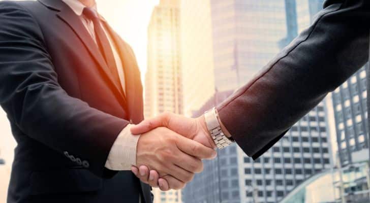 Two men in business suits shaking hands in a city