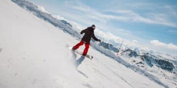 Snowboarder in motion on a snowy mountain slope with clear skies and distant peaks