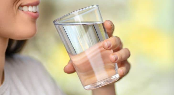 A woman taking a drink from a large glass of water