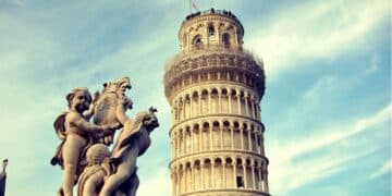 The Leaning Tower of Pisa with a foreground statue of cherubs holding a shield