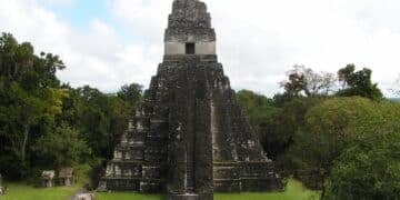 Ancient Maya pyramid in Tikal surrounded by dense greenery showcasing architectural grandeur