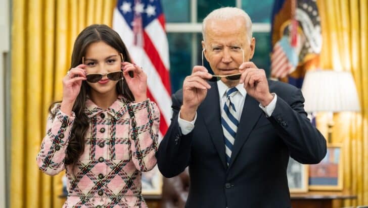 Olivia Rodrigo and President Biden holding sunglasses in front of their faces in the White House