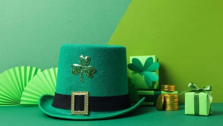 A green top hat with a shamrock, gold coins, green gift boxes, and decorative fans
