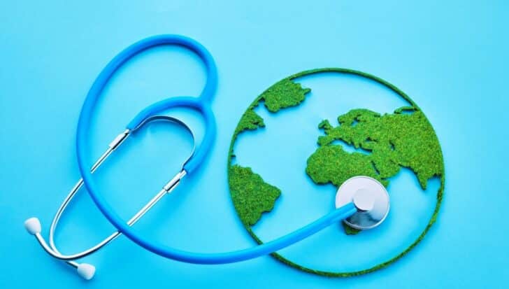 A blue stethoscope placed on a green earth map, symbolizing global health awareness