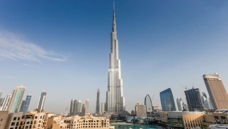 The Burj Khalifa stands prominently in a skyline with other modern buildings under a clear blue sky