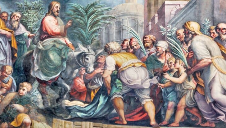 Jesus riding a donkey enters Jerusalem surrounded by people holding palm branches