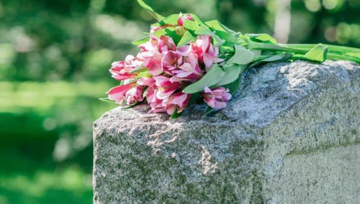 A bouquet of pink and white flowers placed on a gravestone