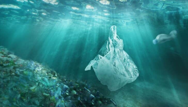 Underwater scene with a floating plastic bag, a plastic bottle, and a pile of plastic debris, illustrating ocean pollution