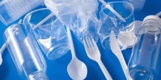 Assorted plastic items, including bottles, cups, a plastic bag, a fork, and a spoon, arranged on a blue background