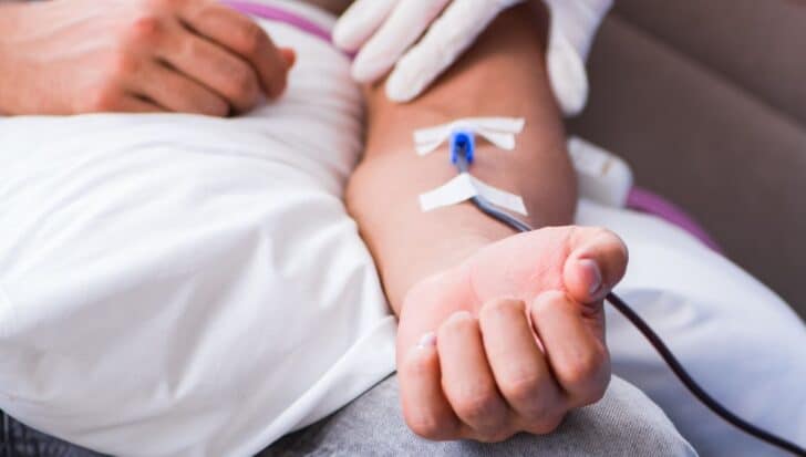 A person receiving a blood draw with a needle in their arm, highlighting the discovery of plastic particles in human blood