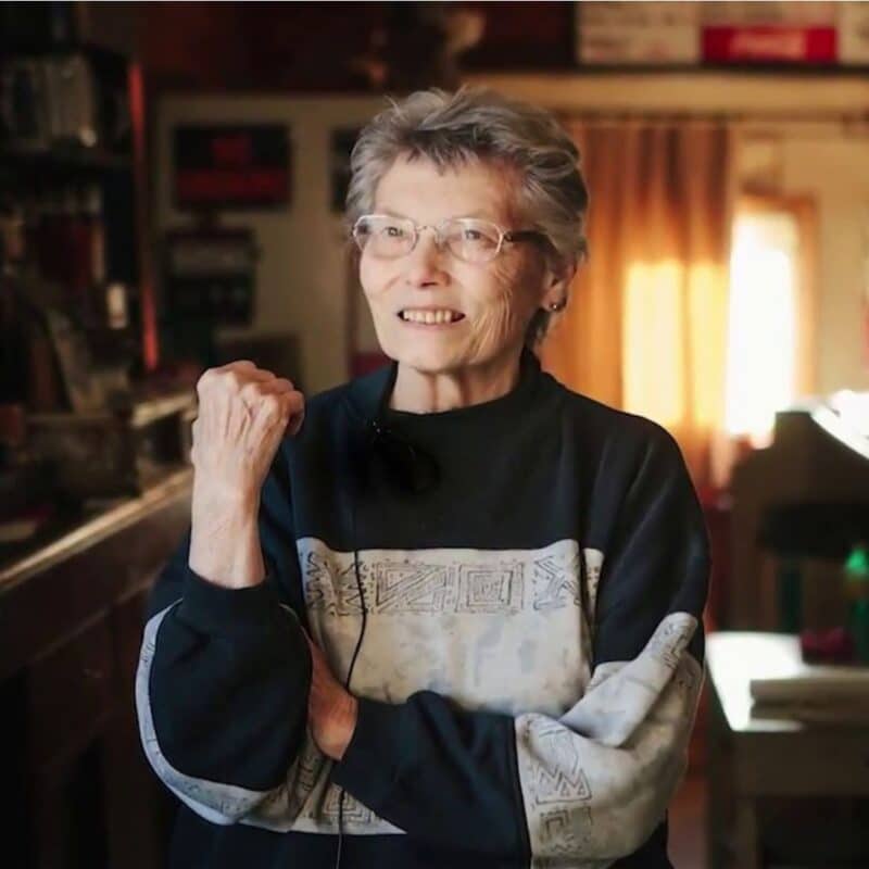 Elsie Eiler, the sole resident and mayor of Monowi, Nebraska, standing inside a warmly lit room