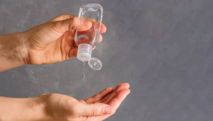 Hands applying liquid from a small bottle onto open palm
